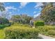 Well-manicured community entrance with lush hedges, green lawns, mature trees, and secure gated access at 1311 Travertine Ter, Sanford, FL 32771