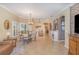 Open-concept dining area with a view of the fireplace, elegant chandelier, and tile floors at 1311 Travertine Ter, Sanford, FL 32771