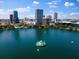 Picturesque aerial view of a city skyline surrounding a tranquil lake with a fountain, amidst lush greenery and parks at 150 E Robinson St # 1214, Orlando, FL 32801