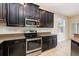 Modern kitchen showcases stainless steel appliances, dark cabinetry, tile backsplash, and granite countertops at 15174 Evergreen Oak, Winter Garden, FL 34787