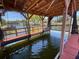 Covered boat dock featuring wooden beams, boatlift, protective netting, and scenic waterfront views at 1522 S Shore Dr, Tavares, FL 32778