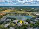 An aerial view of the property surrounded by trees, a pond, and a sunny sky at 167 Villa Di Este Ter Ter # 213, Lake Mary, FL 32746