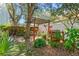 A cozy backyard area with mature trees and a wooden pergola, surrounded by various potted plants at 1709 Palm Beach Dr, Apopka, FL 32712