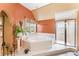 Bathroom with orange walls features a garden tub, a glass shower and a window with natural light at 1709 Palm Beach Dr, Apopka, FL 32712
