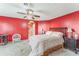 Spacious bedroom with red walls features carpet flooring, ceiling fan, and an arched doorway to the Primary bathroom at 1709 Palm Beach Dr, Apopka, FL 32712