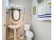 Charming half bathroom with pedestal sink, toilet, and decorative wall hangings at 2263 Mallard Creek Cir, Kissimmee, FL 34743