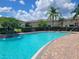 Beautiful community pool featuring brick paver accents, lush landscaping and surrounding community buildings at 2355 Seven Oaks Dr, St Cloud, FL 34772