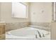 A pristine white corner bathtub surrounded by neutral tilework with chrome fixtures offers a relaxing retreat at 2551 Dharma Cir, Kissimmee, FL 34746