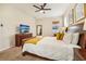 This well-lit bedroom features a ceiling fan, a dresser with a TV, and a brown-framed mirror at 2551 Dharma Cir, Kissimmee, FL 34746