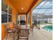 Covered patio area with a dining table, grill, and access to the screened pool and backyard at 2551 Dharma Cir, Kissimmee, FL 34746