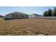 Backyard view of a new home with gray stucco exterior and a large yard and a white fence at 325 Marion Oaks Trail, Ocala, FL 34473