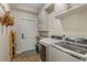 A well-organized laundry room with modern washer and dryer, overhead cabinets, and a door to the outside at 421 E Gore St, Orlando, FL 32806