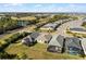 A high-angle shows a suburban neighborhood with homes featuring screened patios, alongside a road and a nearby scenic pond at 5159 Twin Lakes Blvd, St Cloud, FL 34772