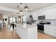 Modern kitchen with white cabinets, stainless steel appliances, an island, and an open view to the living area at 6736 Reverie Park Ave, Orlando, FL 32829