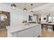 View of kitchen island with white cabinets and quartz countertop, with adjacent dining and living areas at 6736 Reverie Park Ave, Orlando, FL 32829
