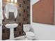 Modern powder room with patterned wallpaper, pedestal sink, a round mirror and sleek fixtures at 6736 Reverie Park Ave, Orlando, FL 32829