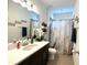Well-lit bathroom featuring a modern vanity, a marble-patterned shower curtain, and neutral-toned walls and flooring at 7035 Oxbow Rd, Minneola, FL 34715
