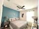 Cozy bedroom with a blue accent wall, ceiling fan, and a comfortable bed with stylish patterned bedding at 7035 Oxbow Rd, Minneola, FL 34715