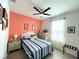 Bright bedroom featuring an accent wall, ceiling fan, and a cozy bed with striped bedding and side tables at 7035 Oxbow Rd, Minneola, FL 34715