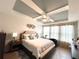 Bright main bedroom boasts a tray ceiling, large windows, and comfortable furnishings at 7035 Oxbow Rd, Minneola, FL 34715