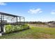 Grassy backyard featuring a pond with a screened in pool area and neighborhood view at 7845 Oak Reflection Loop, Davenport, FL 33837