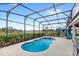Relaxing screened-in pool area with a hot tub, outdoor kitchen and lounge bed at 7845 Oak Reflection Loop, Davenport, FL 33837