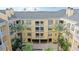 Low-rise building with yellow walls, white balconies, a gray roof and palm trees surrounding the property at 860 N Orange Ave # 326, Orlando, FL 32801