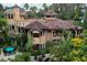 An aerial view reveals a sprawling home with a tile roof, surrounded by tropical landscaping and a pool at 9291 Point Cypress Dr, Orlando, FL 32836
