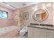 Retro bathroom featuring pink tile, shower-tub combo, granite countertop, and decorative circular mirror at 9291 Point Cypress Dr, Orlando, FL 32836