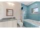 Bright bathroom featuring blue tile, a bathtub, granite counters, and stylish fixtures at 9291 Point Cypress Dr, Orlando, FL 32836