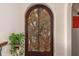Detailed view of an arched door featuring an intricate carved design and greenery at 9291 Point Cypress Dr, Orlando, FL 32836
