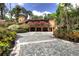 Grand home featuring lush landscaping, a unique stone driveway, and charming architectural details at 9291 Point Cypress Dr, Orlando, FL 32836