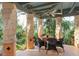 Covered outdoor patio featuring stone pillars, tile flooring, and a seating area overlooking lush landscaping at 9291 Point Cypress Dr, Orlando, FL 32836