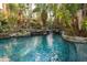 Inviting pool with tropical landscaping and waterfalls, creating a serene and private backyard oasis at 9291 Point Cypress Dr, Orlando, FL 32836