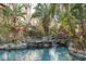 Stunning pool area featuring a rock waterfall, bridge, and lush tropical landscaping for ultimate relaxation at 9291 Point Cypress Dr, Orlando, FL 32836