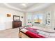 Carpeted bedroom with tray ceiling, large dresser, and window with plantation shutters at 10144 Lake Miona Way, Oxford, FL 34484