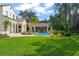 Lush backyard featuring a pool with a rock waterfall and a covered patio, surrounded by tropical landscaping at 11324 Bridge House Rd, Windermere, FL 34786