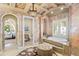 Elegant bathroom with an arched doorway, a soaking tub by a window, and a vanity area at 11324 Bridge House Rd, Windermere, FL 34786