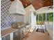 Close up of grill and sink in outdoor kitchen with decorative backsplash and stainless steel appliances at 11324 Bridge House Rd, Windermere, FL 34786