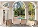 Covered outdoor living space featuring a dining set with a view of a pool and lush landscaping at 11324 Bridge House Rd, Windermere, FL 34786