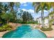 Backyard freeform pool with rock waterfall, lush landscaping and blue skies at 11324 Bridge House Rd, Windermere, FL 34786