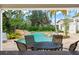 View from covered patio of a pool with a rock waterfall, surrounded by tropical landscaping and lush greenery at 11324 Bridge House Rd, Windermere, FL 34786