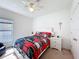 Bright bedroom features a ceiling fan and a comfy bed with a red, black, and gray comforter set at 123 Vitoria Rd, Davenport, FL 33837