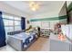 Cozy bedroom features a grey upholstered bed, striped accent wall, and shelves filled with toys at 123 Vitoria Rd, Davenport, FL 33837