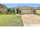 Well-maintained home features lush green grass, a brick driveway, and manicured landscaping at 123 Vitoria Rd, Davenport, FL 33837