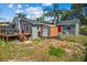 Backyard with a small wooden shed, deck with stairs, and freshly mowed grass and surrounded by trees at 12442 Sunshine Dr, Clermont, FL 34711