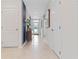 Bright hallway featuring beige tile flooring, decorative mirror, cabinet, and a glass front door at 1251 Big Bass Dr, Ormond Beach, FL 32174