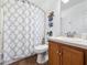 Bathroom with wood vanity, patterned shower curtain, and decorative beach-themed accents at 133 Hillcrest Dr, Davenport, FL 33897