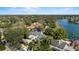 Aerial view of the lakefront home with lush landscaping, circular driveway, and the city skyline in the distance at 1355 S Summerlin Ave, Orlando, FL 32806