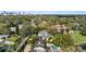 Aerial view of the lakefront home with mature trees, lush landscaping, and the city skyline in the distance at 1355 S Summerlin Ave, Orlando, FL 32806